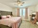Comfortable bedroom with a tufted headboard, carpet, a window with pink drapes, and decorative mirror at 1608 Cross Prairie Pkwy, Kissimmee, FL 34744