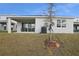 Spacious backyard featuring a covered patio, grass, and a newly planted tree in a new residential community at 5410 Catmint Dr, Lake Hamilton, FL 33851