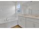 Bright bathroom featuring a double sink vanity, soaking tub, and a large mirror reflecting a glass-enclosed shower at 5410 Catmint Dr, Lake Hamilton, FL 33851