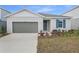 Charming single-story home featuring a grey garage door, blue door, and manicured landscaping at 5410 Catmint Dr, Lake Hamilton, FL 33851