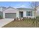 Charming single-story home featuring a grey garage door, blue door, manicured landscaping, and vibrant plants at 5410 Catmint Dr, Lake Hamilton, FL 33851