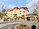 Inviting hotel exterior with covered entrance, manicured landscaping and ample parking on a partly cloudy day at 3000 Maingate Ln # 412, Kissimmee, FL 34747