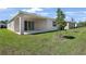 Exterior view of the backyard featuring a covered patio, green grass, and young trees at 4064 Bannock Ave, Tavares, FL 32778
