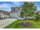 Two story home featuring a two car garage and a front lawn with freshly planted tree at 1769 Carnelian St, Deland, FL 32720