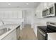 Bright kitchen featuring white cabinetry, stainless steel appliances, and wood-look tile flooring at 1769 Carnelian St, Deland, FL 32720