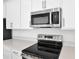 Close-up of stainless steel microwave and electric stove with modern countertops at 5418 Catmint Dr, Lake Hamilton, FL 33851