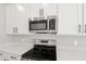 Close-up of stainless steel microwave and oven, and white cabinets in a modern kitchen at 5422 Catmint Dr, Lake Hamilton, FL 33851