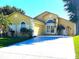 Charming home featuring a two-car garage, well-manicured lawn, and an inviting arched entryway at 2112 Fish Eagle St, Clermont, FL 34714