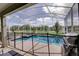 Outdoor pool with black safety fence, screened enclosure and BBQ grill at 712 Whistling Straits Blvd, Davenport, FL 33896