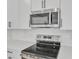 Modern kitchen features stainless steel microwave and electric stovetop with white cabinets and countertops at 3764 Deer Ridge Dr, Mount Dora, FL 32757