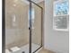 Modern shower with a glass door, neutral tiles, and natural light from two adjacent windows at 3764 Deer Ridge Dr, Mount Dora, FL 32757