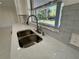 Kitchen sink featuring stainless steel faucet, window, and stone countertops at 2728 Adair Rd, Davenport, FL 33837