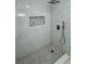 Modern shower with marble-style tiles, mosaic floor, and recessed shelf for bath products at 2728 Adair Rd, Davenport, FL 33837