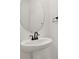 Modern powder room with white pedestal sink, black faucet, round mirror and a towel holder at 3724 Deer Ridge Dr, Mount Dora, FL 32757