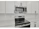 Close-up of kitchen featuring stainless steel appliances, white cabinets, and subway tile backsplash at 3724 Deer Ridge Dr, Mount Dora, FL 32757