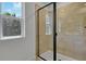 Tiled shower enclosure featuring glass door, neutral tiling, and a window for natural light at 3724 Deer Ridge Dr, Mount Dora, FL 32757
