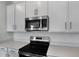A close-up of a modern black stove, stainless steel microwave, and white cabinets at 652 Hennepin Loop, Lake Wales, FL 33898