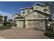 Beautiful two-story home showcasing a brick paved driveway, two-car garage, and well-manicured landscaping at 1222 Castlevecchio Loop, Orlando, FL 32825