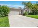 Traditional home featuring a two-car garage and driveway with beautiful mature landscaping at 1569 Thetford Cir, Orlando, FL 32824