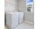 Laundry room with modern washer and dryer, light tile flooring, and a bright window at 3824 Deer Ridge Dr, Mount Dora, FL 32757