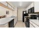 Bright kitchen featuring ample cabinet space, black appliances, double sink and tile flooring at 3151 Britannia Blvd # C, Kissimmee, FL 34747