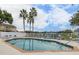 Community swimming pool and lounge area surrounded by a white fence and palm trees at 8716 Rain Forest Pl # D, Kissimmee, FL 34747