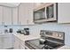 Modern kitchen with stainless steel appliances, white cabinets and countertops, and tile backsplash at 8932 Cabot Cliffs Dr, Davenport, FL 33896