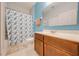 Bright bathroom with a vanity, toilet, shower with seashell-themed curtain, and white tile flooring at 1819 Coriander Dr # 1819, Kissimmee, FL 34759