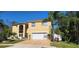 Two-story home with a two-car garage, lush landscaping, and a screened in front porch, creating a charming curb appeal at 2606 Royal Fern Pl, Kissimmee, FL 34758