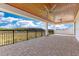 Covered outdoor patio with stone flooring, ceiling fans and black railing overlooking nature at 13809 Abberwick Dr, Orlando, FL 32832