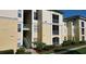 A daytime shot shows an exterior view of the light yellow apartment building with its concrete stairs at 8910 Legacy Ct # 206, Kissimmee, FL 34747