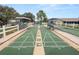 A shuffleboard court features green courts, covered benches, and a bright, fenced recreation area at this community at 392 Winter Ridge Blvd # 105, Winter Haven, FL 33881