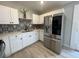 An updated kitchen with stainless steel fridge, white cabinets, quartz countertops, and decorative backsplash at 101 Gerry Dr, Altamonte Springs, FL 32714