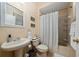 Small bathroom with a pedestal sink, toilet, and shower with curtain at 18035 Cadence St, Orlando, FL 32820