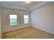 Bright bedroom with neutral carpet, tray ceiling, and two windows offering natural light and views at 6078 Bimini Twist Loop, Orlando, FL 32819