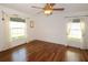 Bright bedroom featuring hardwood floors, a fan, and two windows with curtains and rods at 504 Ridge View Dr, Davenport, FL 33837