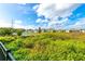 Community homes are visible beyond the lush green backyard and pond that sits near this home at 527 Noble Ave, Davenport, FL 33837