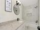 Bathroom with white vanity, granite countertop, stylish mirror, and shower over tub with modern tile at 1234 Lynwood Ave, Apopka, FL 32703