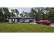 Single story home with gray exterior, two car garage, landscaping and red SUV at 6817 Sw 131St Pl, Ocala, FL 34473