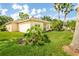 Well-maintained backyard featuring a lush green lawn, tropical plants, and a home exterior at 753 Largo Pass, Poinciana, FL 34759