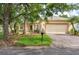 Charming single-story home with a well-manicured lawn, mature trees, and a brick driveway leading to an attached two-car garage at 753 Largo Pass, Poinciana, FL 34759