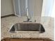 Close-up of a granite kitchen sink with a sleek chrome faucet and views of the bright window, offering a touch of elegance at 753 Largo Pass, Poinciana, FL 34759