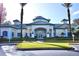 Exterior view of the community clubhouse, surrounded by lush landscaping and palm trees at 8830 Dunes Ct # 12 207, Kissimmee, FL 34747