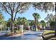 View of community entrance with gated access for residents, palm trees, and landscaping at 8830 Dunes Ct # 12 207, Kissimmee, FL 34747
