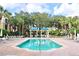 Sparkling community pool with lounge chairs and shaded cabanas under a sunny sky at 8830 Dunes Ct # 12 207, Kissimmee, FL 34747