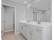 Bathroom featuring double sinks, white cabinets, and large mirror above the sink with an open door leading to the toilet at 5414 Catmint Dr, Lake Hamilton, FL 33851