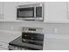 Close-up showcasing stainless steel microwave and stove with white cabinetry at 5414 Catmint Dr, Lake Hamilton, FL 33851