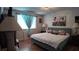 Bedroom features bed with beach art piece, window with drapes, and bedside lamps; showcasing cozy ambiance at 1600 W Lake Parker Dr # B23, Lakeland, FL 33805