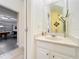 Cozy bathroom with a white vanity, decorative mirror, and a doorway view to a garage and game room at 4191 Oaktree Drive, Davenport, FL 33837