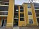 Exterior of yellow two-story apartment complex showing stairways and walkways at 5267 Images Cir # 303, Kissimmee, FL 34746